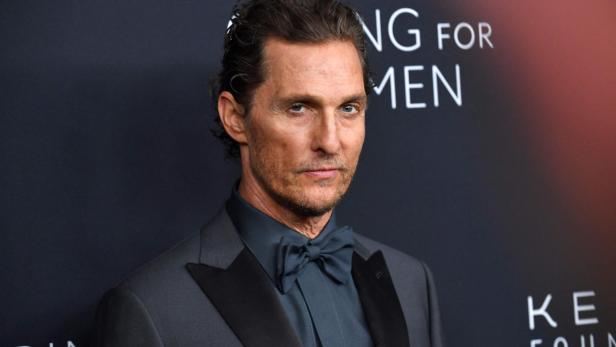 Matthew McConaughey trägt einen dunklen Anzug mit Fliege vor einem Hintergrund mit der Aufschrift „Kering Foundation“.