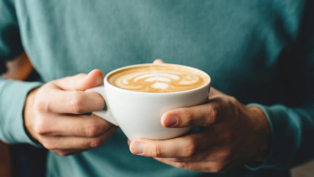 The cup of cappuccino in men's hands