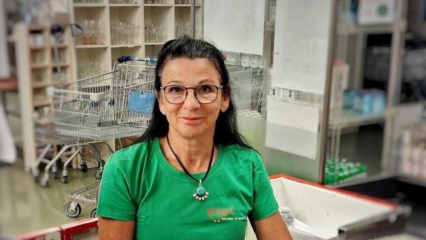 Frau an der Kasse eines Supermarkts mit mehreren Lebensmitteln vor ihr.