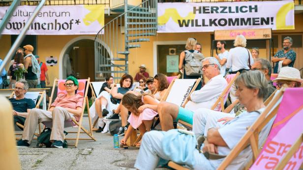 Mehrere Leute sitzen in einem Innenhof in Liegestühlen. 