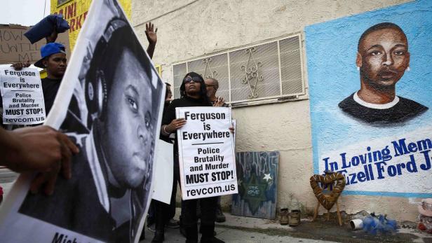 Demonstranten halten Schilder mit der Aufschrift „Ferguson is Everywhere“ vor einem Wandgemälde von Ezell Ford Jr..