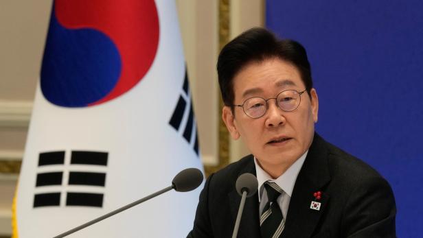 Der südkoreanische Politiker Lee Jae-myung spricht vor Mikrofonen vor der Flagge Südkoreas.