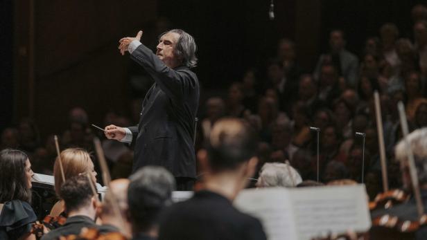 Riccardo Muti dirigiert ein Orchester vor einem Publikum in einem Konzertsaal.
