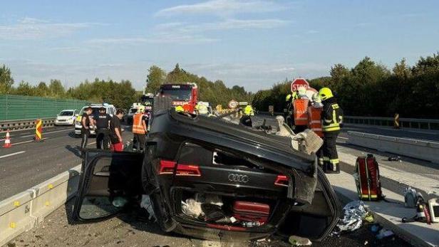 Umgestürztes Auto auf der Autobahn, Rettungskräfte im Einsatz.