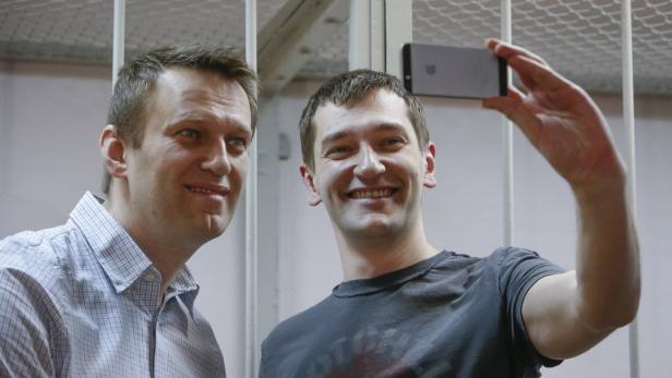 Gute Miene zum bösen Spiel: Während das Urteil verlesen wird, amüsieren sich Alexei und Oleg Nawalny (re.) demonstrativ mit Selfies.