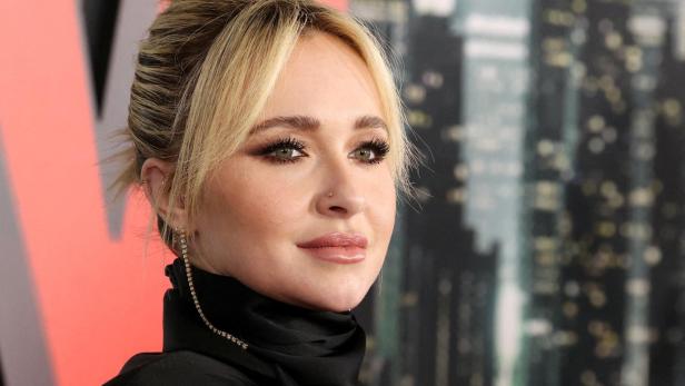 Hayden Panettiere mit blondem Dutt und schwarzem Oberteil vor einem verschwommenen Hintergrund.