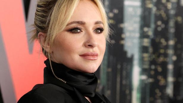 Hayden Panettiere mit blondem Dutt und schwarzem Oberteil vor einem verschwommenen Hintergrund.