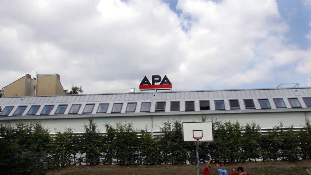 Ein Gebäude mit dem APA-Logo und einem Basketballkorb im Vordergrund.