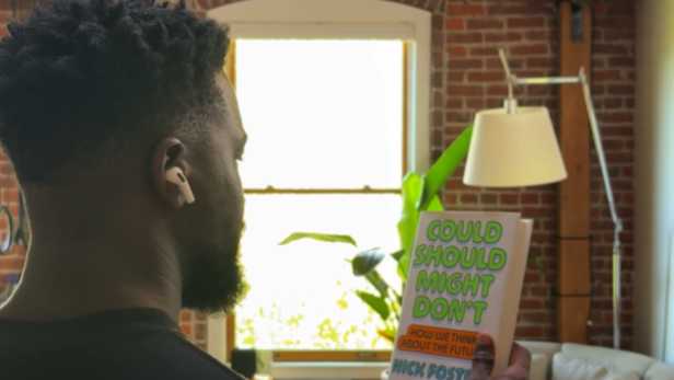 Ein Mann trägt Apple AirPods und hält ein Buch in der Hand