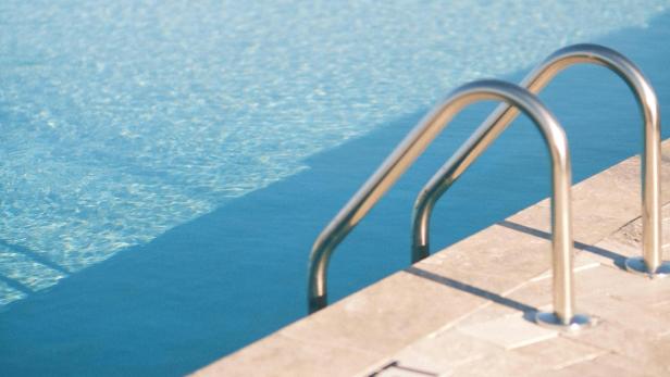 Leere Schwimmbadleiter am Beckenrand.