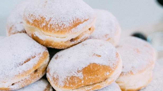 Mit Puderzucker bestreute Krapfen auf einem Teller.