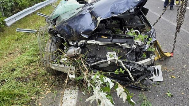 Schwer verunfalltes Auto auf der Straße, Einsatzkräfte sichern die Unfallstelle.