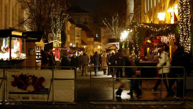Ein belebter Weihnachtsmarkt in einer Stadt bei Nacht.