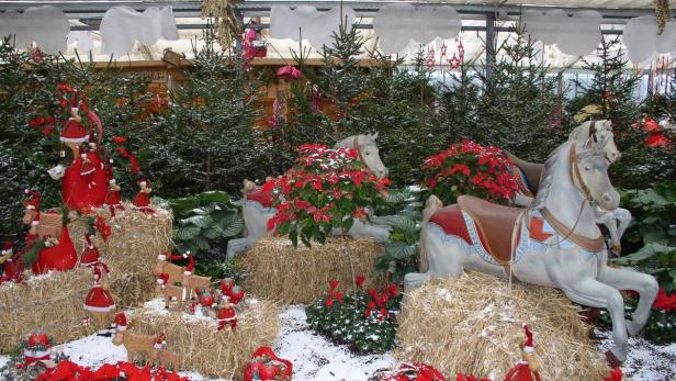 Weihnachtsdekoration mit Spielzeugpferden, Strohballen und kleinen Weihnachtsmannfiguren.