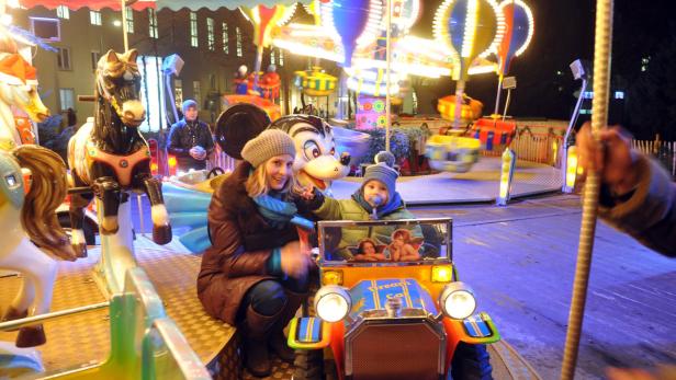 Eine Frau und ein Kind sitzen in einem Auto auf einem Karussell.