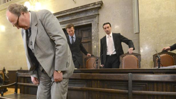 Ein Mann im Anzug beugt sich in einem Gerichtssaal nach vorne.