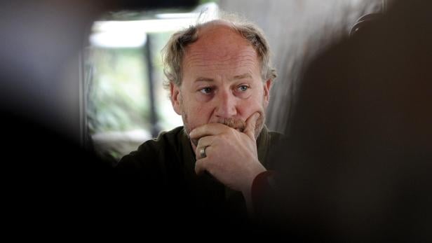 Ein Mann mit Bart und Ring am Finger denkt nachdenklich.