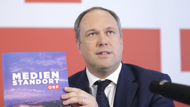 Ein Mann im Anzug präsentiert eine Broschüre mit dem Titel „Medien Standort ORF“.