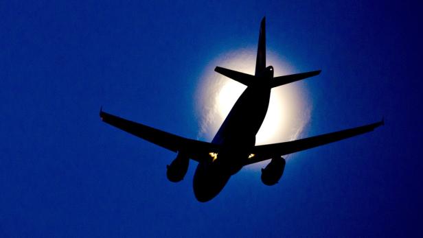 Die Silhouette eines Flugzeugs vor einem hellen, blauen Himmel.