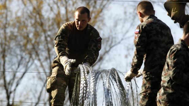 Slowenische Soldaten bauen einen Stacheldrahtzaun an der Grenze zu Kroatien.