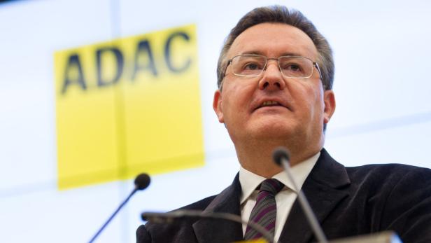 Ein Mann mit Brille spricht vor einem gelben ADAC-Logo.