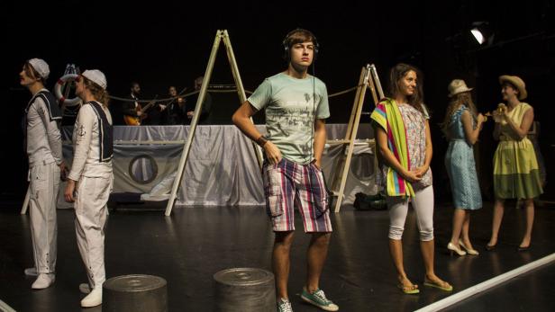 Eine Theaterszene mit Schauspielern in verschiedenen Kostümen auf einer Bühne.