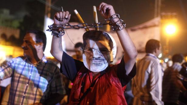 An anti-Mursi protester wears a mask depicting deposed president Mohamed Mursi, and chains on his hands, close to the presidential palace in Cairo July 19, 2013. Thousands of Mursi&#039;s supporters took to the streets of Egyptian cities on Friday to demand the reinstatement of the Islamist leader. However, Egypt&#039;s armed forces, which shunted the country&#039;s first freely elected president from office less than three weeks ago, looked in no mood to make concessions, putting on a show of force in the hazy skies above Cairo. REUTERS/Asmaa Waguih (EGYPT - Tags: POLITICS CIVIL UNREST MILITARY)