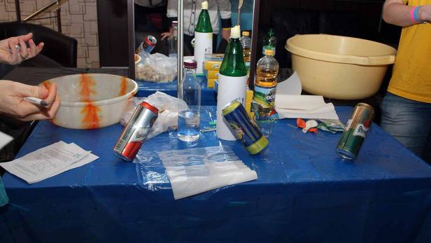 Auf einem blauen Tisch stehen Getränke, Schüsseln und andere Gegenstände.