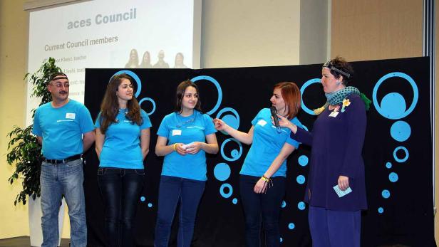 Eine Gruppe von Personen steht auf einer Bühne während einer Präsentation des „aces Council“.