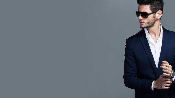 Ein Mann mit Sonnenbrille und Anzug blickt zur Seite.