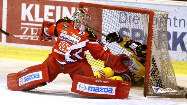 Ein Eishockeytorwart in roter Ausrüstung wehrt einen Schuss ab.