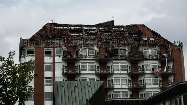 Ein mehrstöckiges Gebäude mit Brandschäden am Dach und an den oberen Stockwerken.