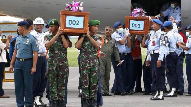 Soldaten tragen Särge mit Blumen vom Flugzeug.