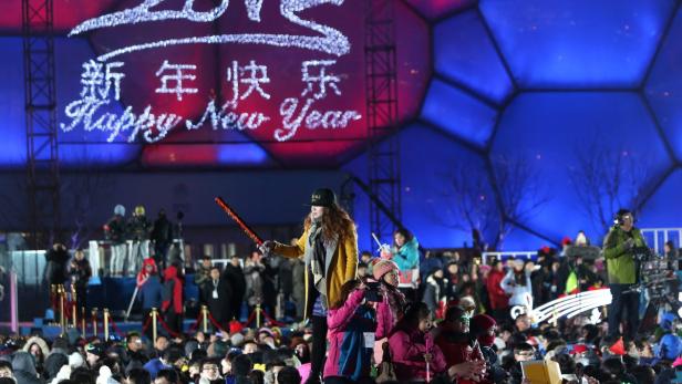 Eine Menschenmenge feiert das chinesische Neujahr vor einer Bühne mit der Aufschrift „Happy New Year“.