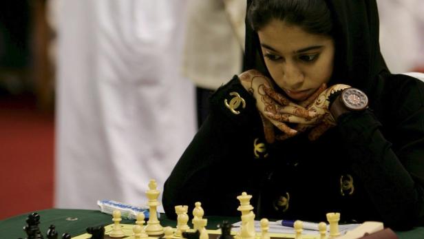 Eine asiatische Schachspielerin mit Schleier bei einem Turnier.