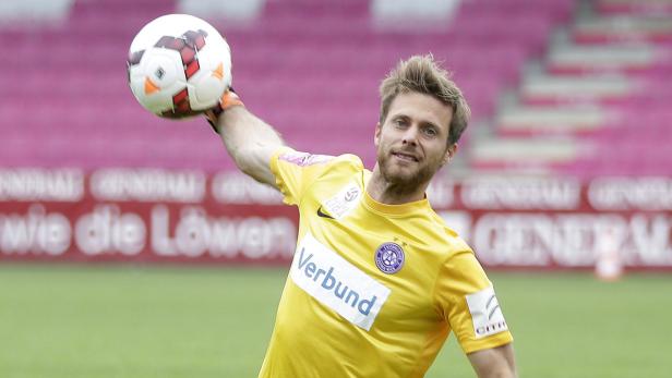 Ein Fußballspieler in gelbem Trikot hält einen Ball in der Hand.