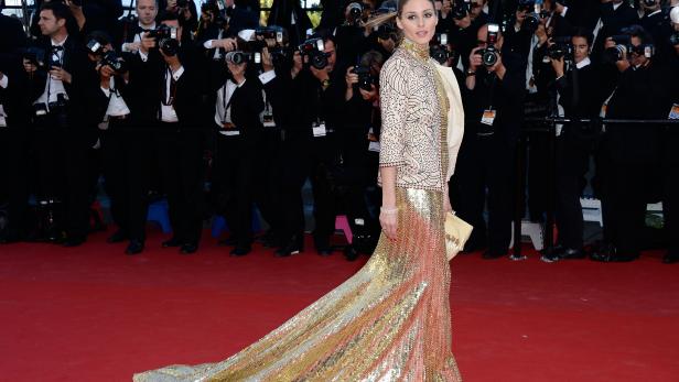 Olivia Palermo posiert auf dem roten Teppich vor einer Wand von Fotografen.