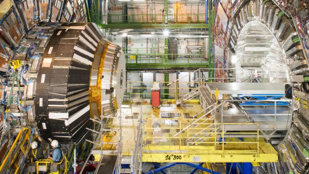 Das Innere des Compact Muon Solenoid (CMS) Detektors am CERN, mit zwei Arbeitern im Vordergrund.