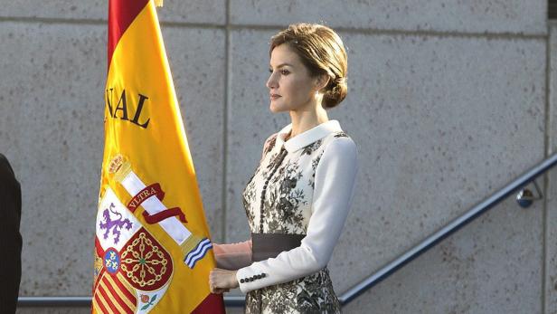 Königin Letizia von Spanien steht neben der spanischen Flagge.