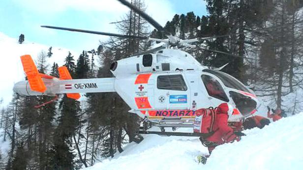 Ein Notarzthubschrauber landet im Schnee, während Sanitäter bereitstehen.