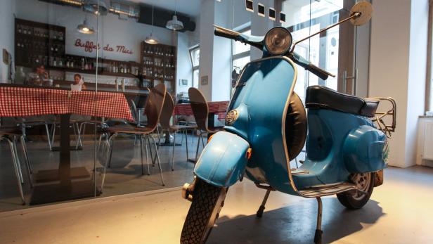 Eine hellblaue Vespa steht in einem Café.