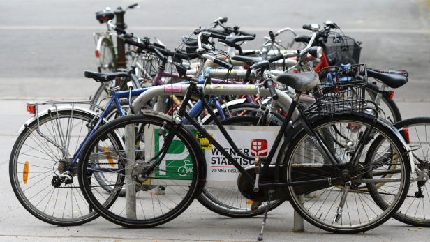 Viele Fahrräder stehen an einem Fahrradständer in Wien.