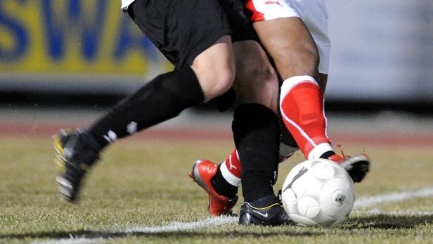 Zwei Fußballspieler kämpfen um den Ball auf dem Spielfeld.