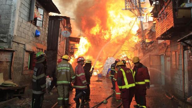 Feuerwehrleute bekämpfen einen Brand in einem dicht bebauten Wohngebiet.
