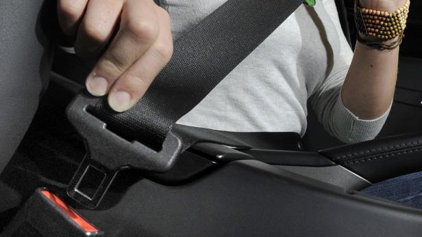Eine Person schließt den Sicherheitsgurt im Auto.
