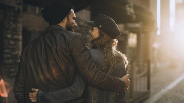 Ein Paar in warmer Kleidung umarmt sich in einer Stadtstraße.