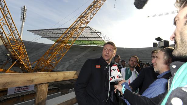 Ein Mann wird vor dem Hintergrund des Stadionbaus interviewt.