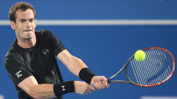 Andy Murray schlägt einen Tennisball vor blauem Hintergrund.