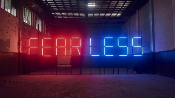 Die Leuchtreklame „FEARLESS“ in Rot und Blau steht in einem verlassenen Raum.