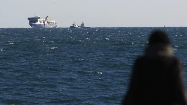 Ein großes Schiff und zwei Schlepper auf dem offenen Meer.